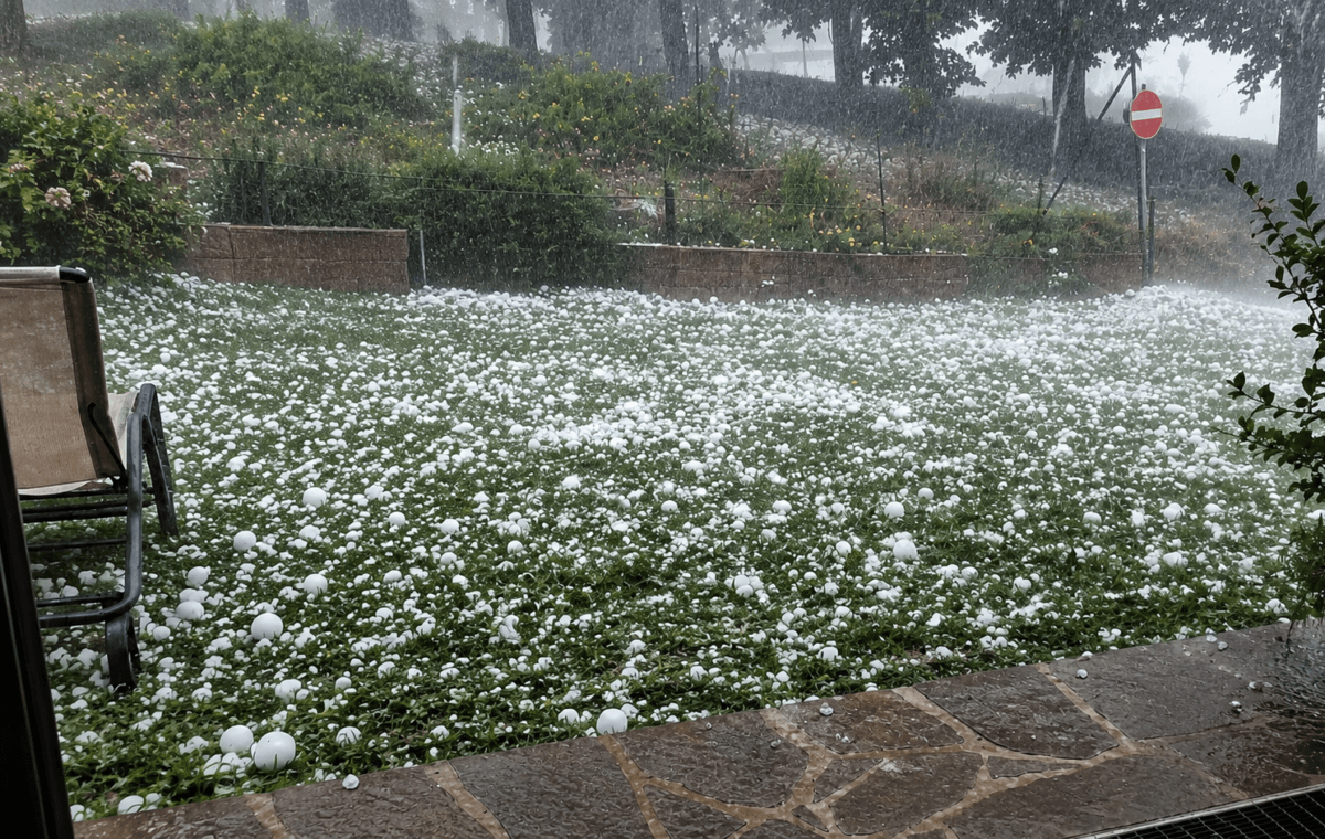 Frame real aprimorado por IA mostra forte chuva de granizo cobrindo um gramado com pedras de gelo.