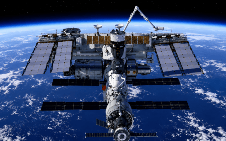 Ilustração de IA mostra a Estação Espacial Internacional orbitando a Terra, tema de passagem visível no Brasil.