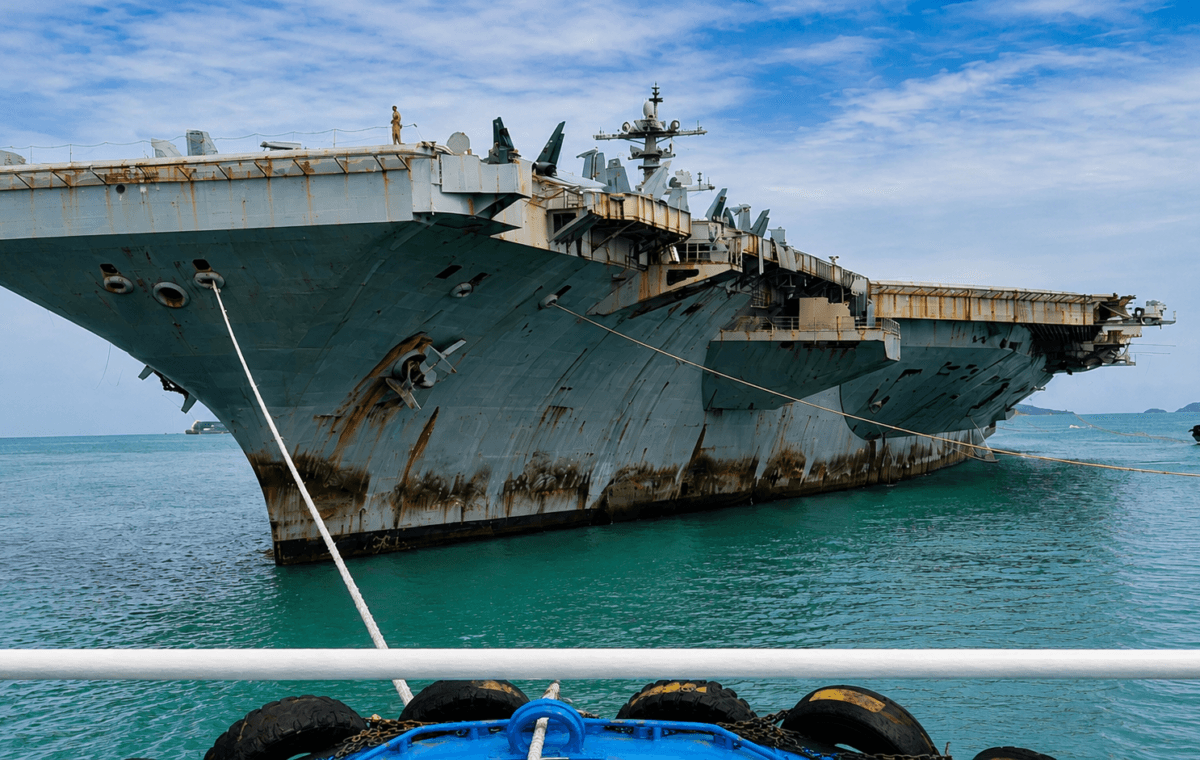 Frame real aprimorado por IA mostra o USS Abraham Lincoln com marcas de ferrugem no casco durante chegada à Tailândia.