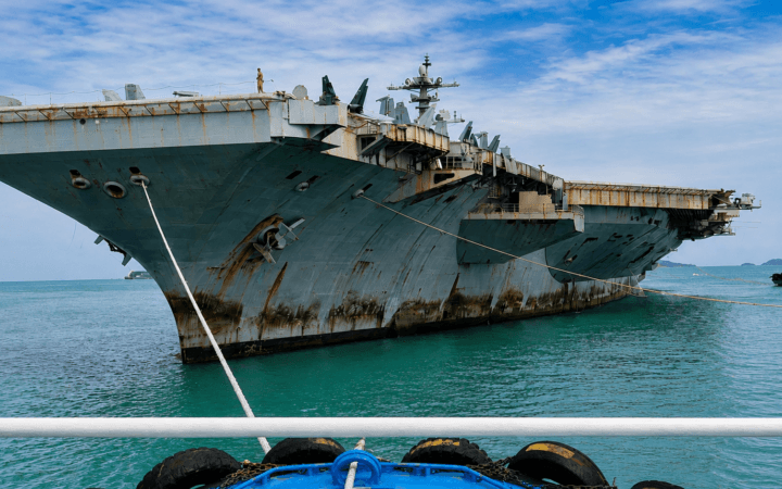 Frame real aprimorado por IA mostra o USS Abraham Lincoln com marcas de ferrugem no casco durante chegada à Tailândia.